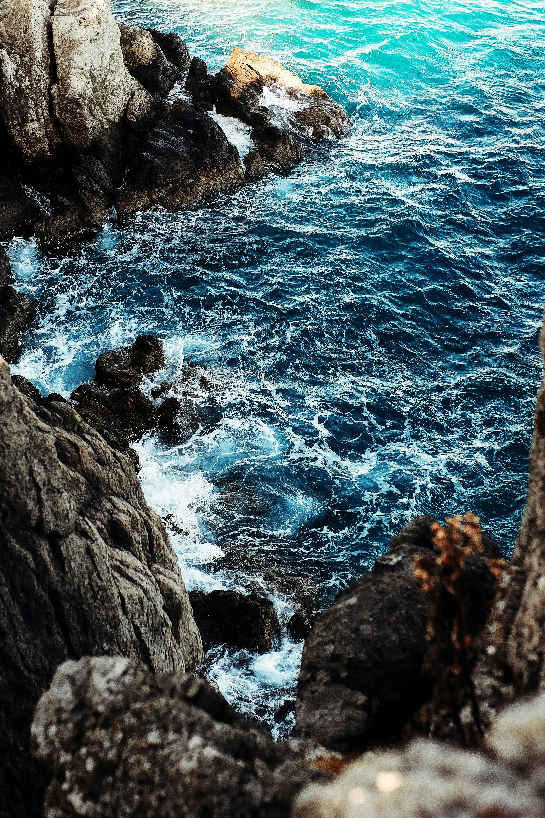 brown rocky mountain beside blue sea during daytime